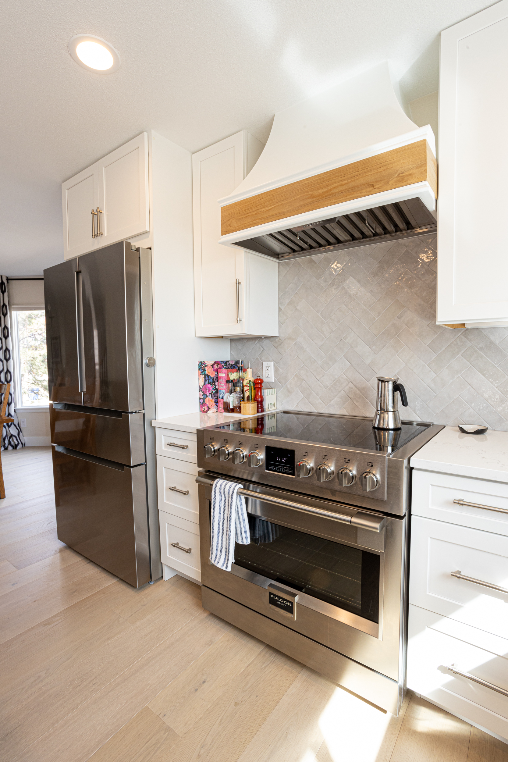 Herringbone tile backsplash with stovetop and range hood